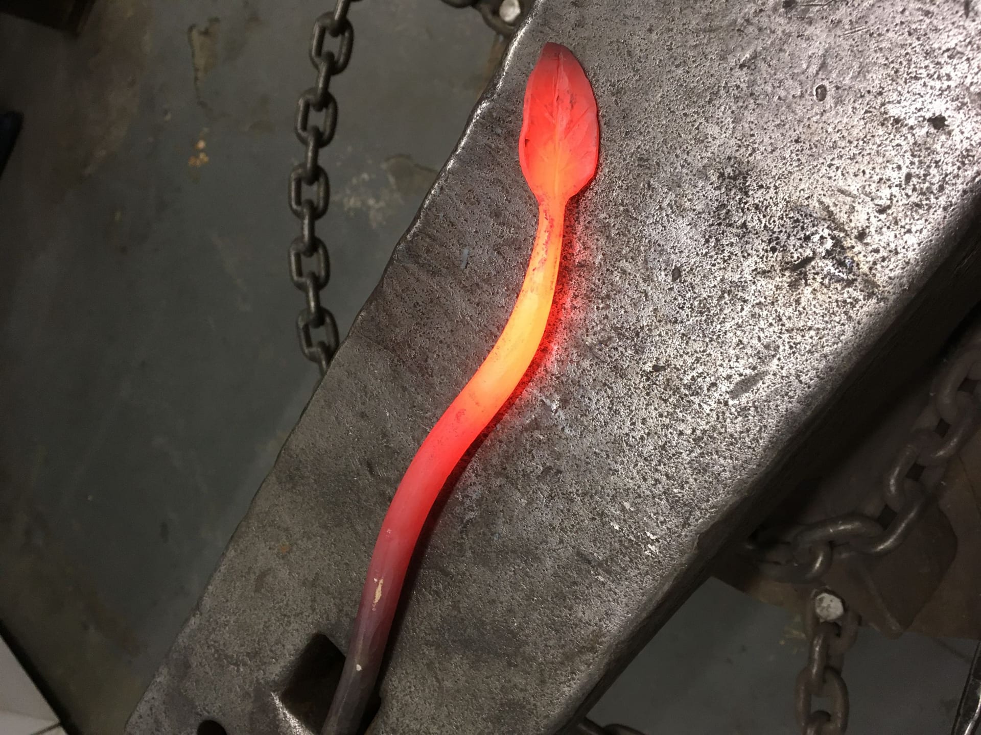 A leaf glowing orange on the anvil, part way through the work